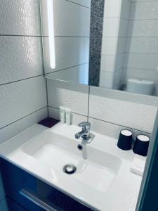 een witte wastafel in een badkamer met een spiegel bij logis Paul Massy in Meschers-sur-Gironde