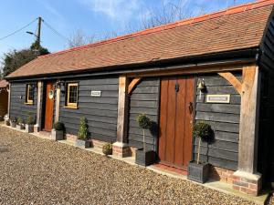 a black shed with a brown roof and potted plants at The Lodge in Little Clacton
