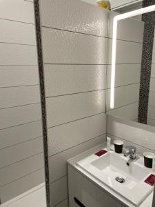 een badkamer met een witte wastafel en een spiegel bij logis Paul Massy in Meschers-sur-Gironde