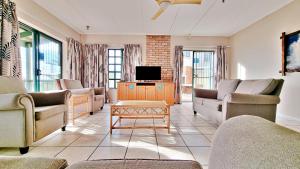 sala de estar con sofás y TV de pantalla plana. en Settler Sands Resort - Holsboer Vacations, en Port Alfred
