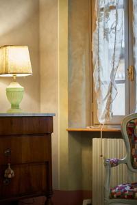 eine Lampe auf einer Kommode neben einem Fenster in der Unterkunft Alla Scala 1746 in Siena