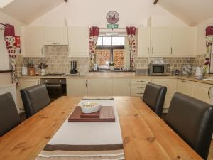 a kitchen with a wooden table with chairs around it at The Barn in North Burton