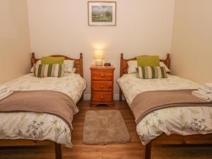 a bedroom with two beds and a dresser with a lamp at The Barn in North Burton