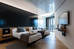 Borgo San Barbato Resort Spa & Golf في Lavello: غرفة نوم بها سريرين وتلفزيون بشاشة مسطحة