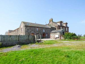 an old brick house with a fence in a field at Surprise View in Holmrook