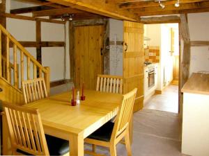 a dining room with a wooden table and a kitchen at Point Cottage in Blakemere