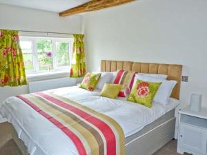 a bedroom with a bed with colorful pillows and a window at Chimney Gill in Sebergham