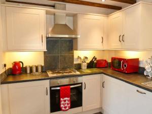 uma cozinha com armários brancos e um forno com placa de fogão em Beudy Bach em Abergele