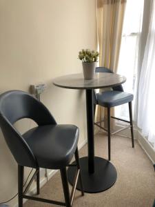 a table with two chairs and a table with a plant on it at Bella Vista Hotel in Weston-super-Mare