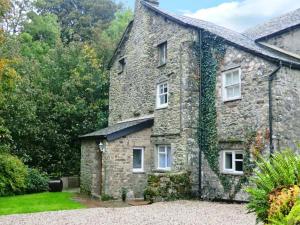an old stone house with ivy growing on it at Beckside Cottage in Mansergh