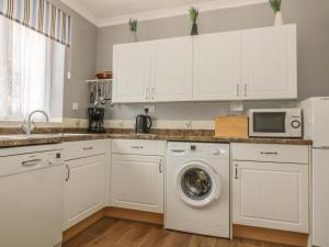 uma cozinha com armários brancos e uma máquina de lavar roupa em The Bungalow em Ipswich