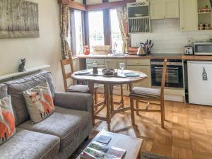 ein Wohnzimmer mit einem Sofa und einem Tisch in der Küche in der Unterkunft Fox Cottage in Droitwich