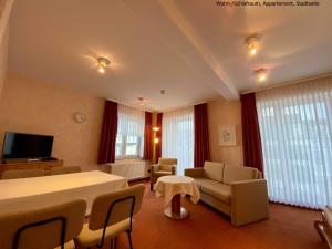 Hotel Meeresburg في نورديرني: غرفة معيشة مع طاولة وكراسي وتلفزيون