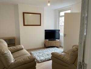 Poplar street Contractors & Leisure by Leecroft Stays في ويلينغبوره: غرفة معيشة مع أريكة وتلفزيون بشاشة مسطحة