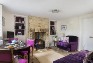 a living room with purple furniture and a fireplace at Church Cottage in Chipping Norton