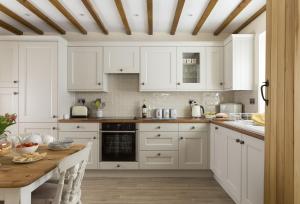 a kitchen with white cabinets and a wooden table at Alysas Cottage in Chipping Norton