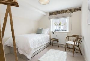 ein Schlafzimmer mit einem Bett, einem Stuhl und einem Fenster in der Unterkunft The Bakery in Moreton-in-Marsh