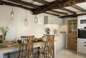a kitchen with white cabinets and a table with chairs at Corner Cottage in Adlestrop