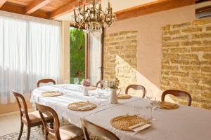 een eetkamer met een witte tafel met stoelen en een kroonluchter bij Albergue LaMorena in Ledigos