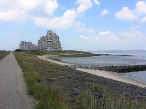 un sentiero accanto a una spiaggia con un edificio di Kustverhuur, Prachtig appartement met uitzicht op zee, Port Scaldis 09-051 a Breskens