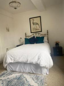 a bedroom with a large white bed with blue pillows at Mingo Cottage in Bewdley