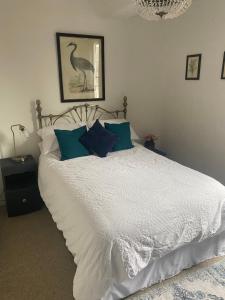 a bedroom with a white bed with blue pillows at Mingo Cottage in Bewdley