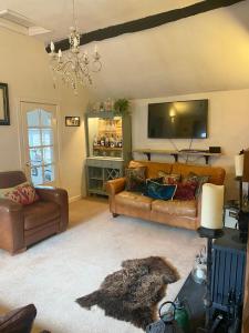 a living room with two couches and a television at Mingo Cottage in Bewdley