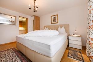 a bedroom with a large white bed and a chandelier at Hotel Montabella in Schruns-Tschagguns
