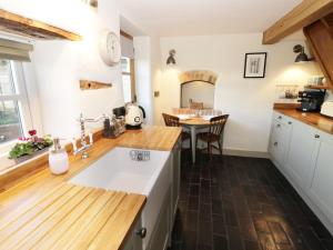 cocina con fregadero y encimera de madera en Ivy Cottage, en Great Malvern