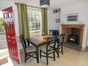 a dining room with a table and chairs and a fireplace at 1 Willow Cottage in Upton upon Severn