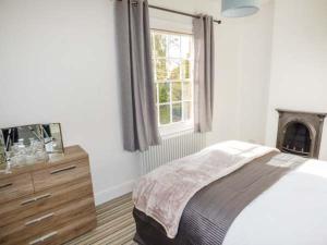 a bedroom with a bed and a dresser and a window at 1 Willow Cottage in Upton upon Severn