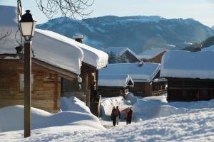 three people walking in the snow near a house at Studio Danay in Le Grand-Bornand