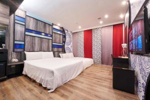 a bedroom with a large white bed and a flat screen tv at Catwalk Motel -Tainan in Tainan