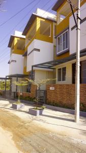 DayOne Suites في بانغالور: مبنى اصفر وابيض وامامه اشجار