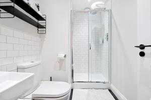 y baño blanco con aseo y ducha. en Norman Road- Brand new luxury GF Apartment, en St. Leonards