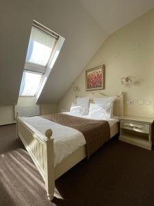 1 dormitorio con 1 cama blanca grande y ventana en Monomakh Hotel, en Vladimir
