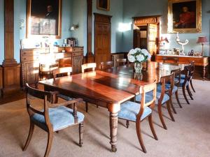 uma sala de jantar com uma mesa de madeira e cadeiras em Dalvey House em Forres