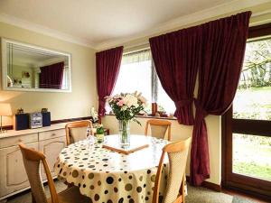 ein Esstisch mit einer Vase mit Blumen darauf in der Unterkunft Chy Lowenna in Saint Cleer