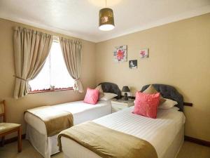 ein Schlafzimmer mit zwei Betten mit rosa Kissen in der Unterkunft Chy Lowenna in Saint Cleer