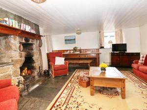 a living room with a stone fireplace and a table at Westroose Farm House in Otterham