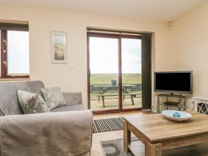 a living room with a couch and a tv and a table at Sea Horses in Marazion