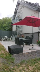 um pátio com uma mesa e um guarda-chuva vermelho em Klimatisiertes Ferienapartment an der Stadtgrenze von Berlin em Gosen