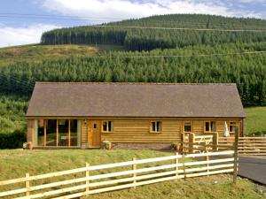 una casa de madera en un campo con una valla en Happy Union Stables, en Abbey-Cwmhir