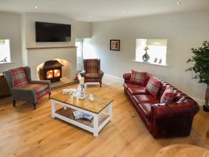 a living room with couches and a table and a fireplace at Ox Hey Barn in Bolton by Bowland