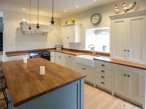 a kitchen with white cabinets and a wooden counter top at Ox Hey Barn in Bolton by Bowland