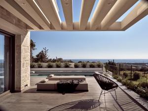 a patio with a couch and a table and chairs at Alexandra SeaView Luxurious Villa, By ThinkVilla in Vasilikos