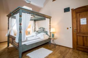a bedroom with a canopy bed and a wooden floor at Gastland M1 Hotel & Conference Center in Páty +28 photos