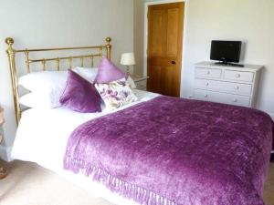 ein Schlafzimmer mit einer lila Decke auf einem Bett in der Unterkunft Gavel Cottage in Bowness-on-Windermere