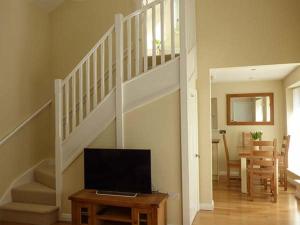 a living room with a staircase and a television at Setch Barn in Masham