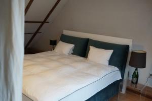 a white bed with a green headboard and white pillows at La Mosu in Porumbacu de Sus